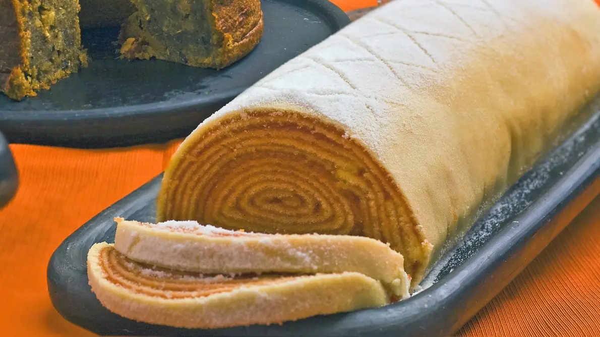 Bolo de rolo com dois pedaços cortados em travessa.