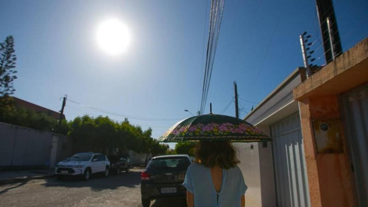 Mulher caminha em caçada sob o Sol em Fortaleza