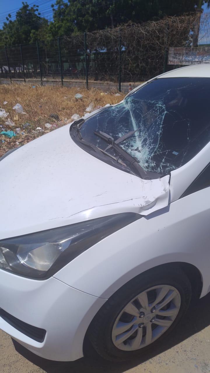 Veículo branco com para-brisa rachado devido à queda de poste.