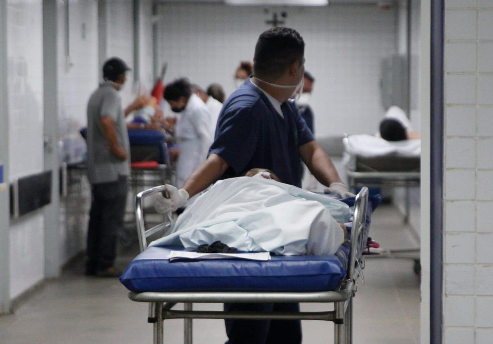 Foto mostra profissional de saúde conduzindo maca com paciente nos corredores do Instituto Dr. José Frota (IJF).