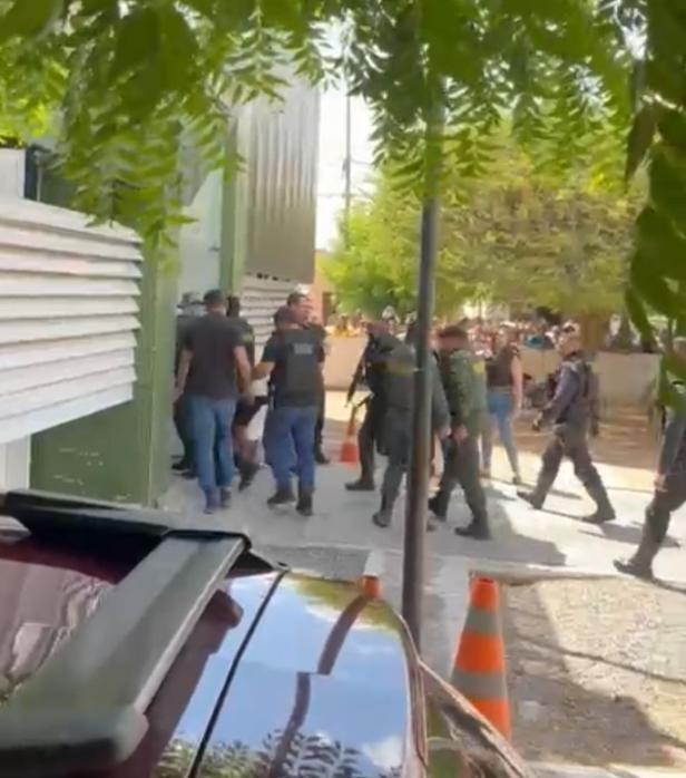A foto mostra vários policiais em volta de um suspeito preso por um sequestro, em frente a uma delegacia, em Jaguaribe, no Interior do Ceará.