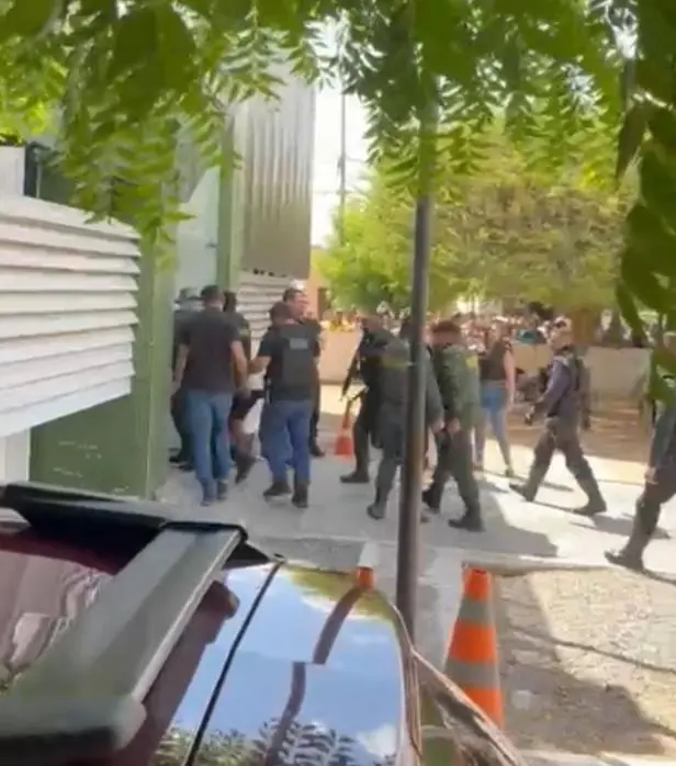 A foto mostra vários policiais em volta de um suspeito preso por um sequestro, em frente a uma delegacia, em Jaguaribe, no Interior do Ceará.