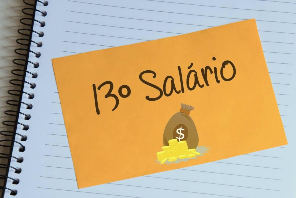 Foto mostra um bilhete dizendo décimo terceiro salário sobre um caderno.