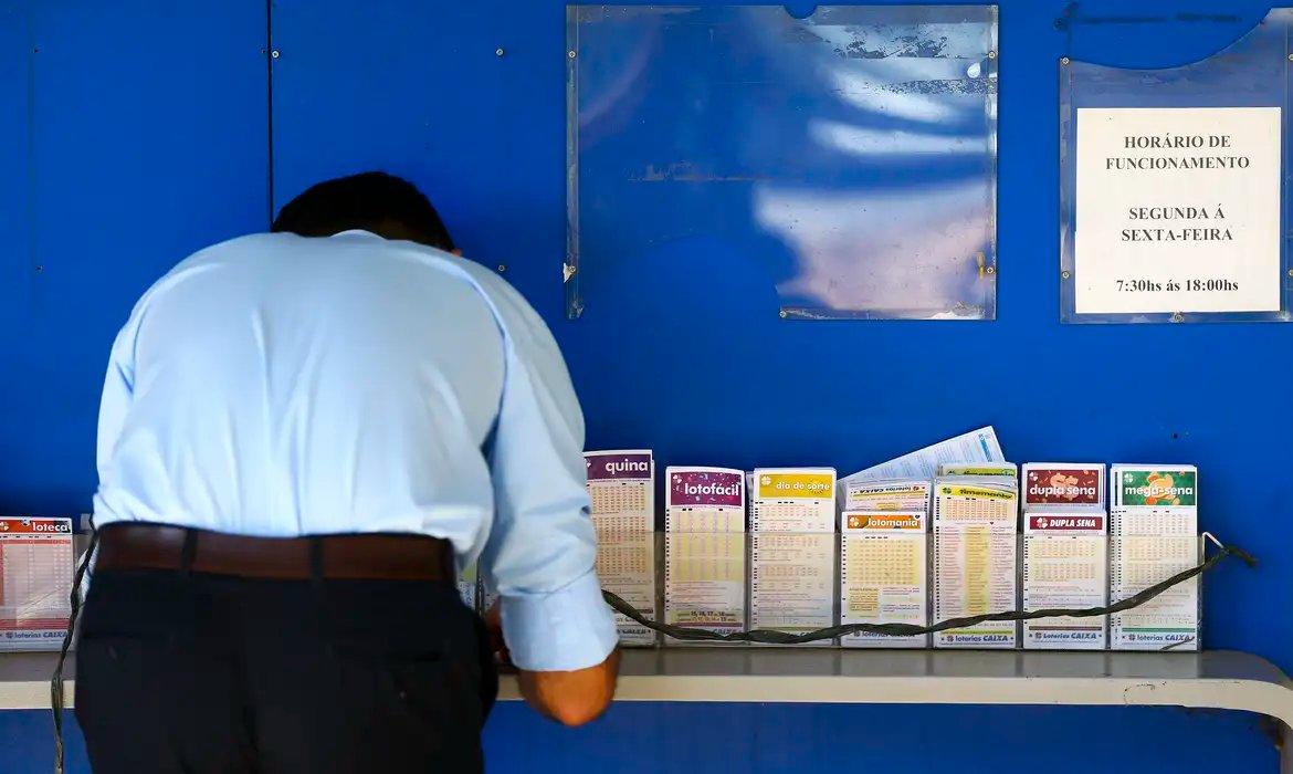 Homem marca cartela de apostas da loteria.