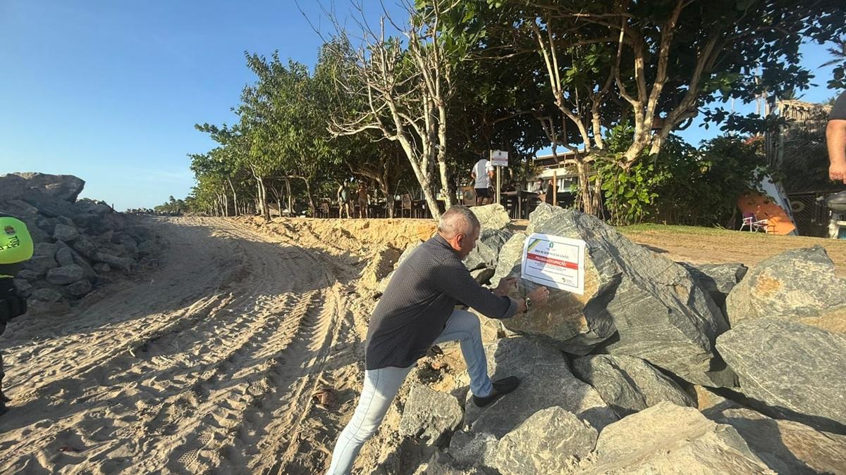 Servidor da Secretaria de Patrimônio da União fixa aviso de obra embargada na Praia de Jericoacoara