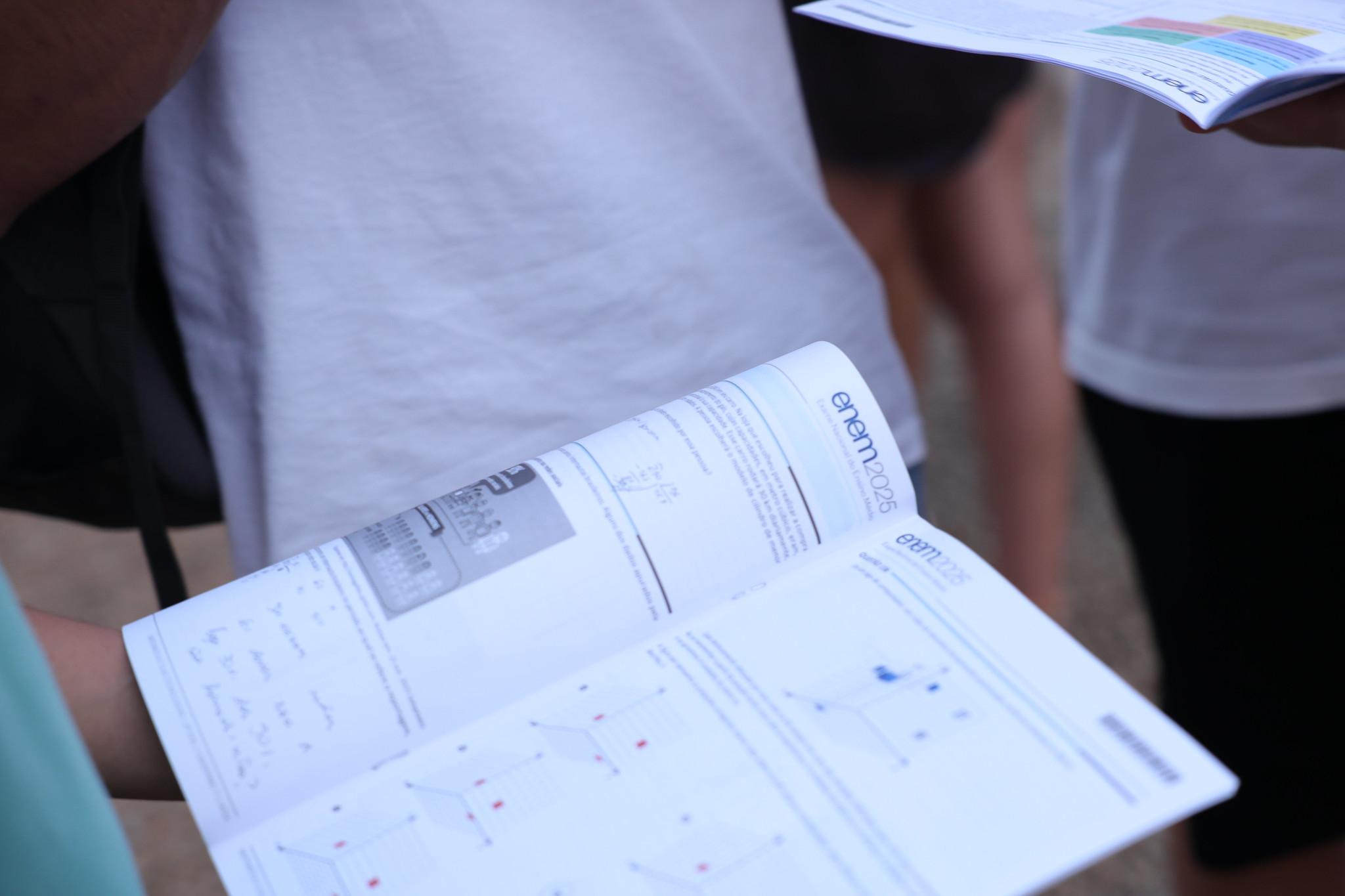 Estudantes segurando caderno de provas do Enem 2025 após realização da prova no Brasil.