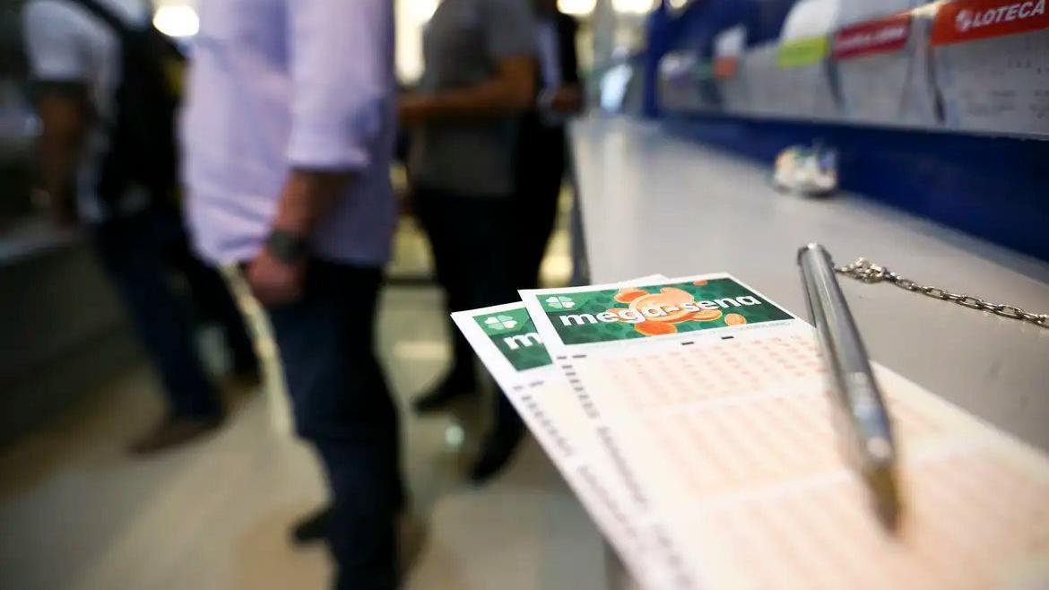 Cliente comprando bilhetes na loteria Mega-Sena em uma loja de apostas, com foco nas apostas e no painel de loteria ao fundo.