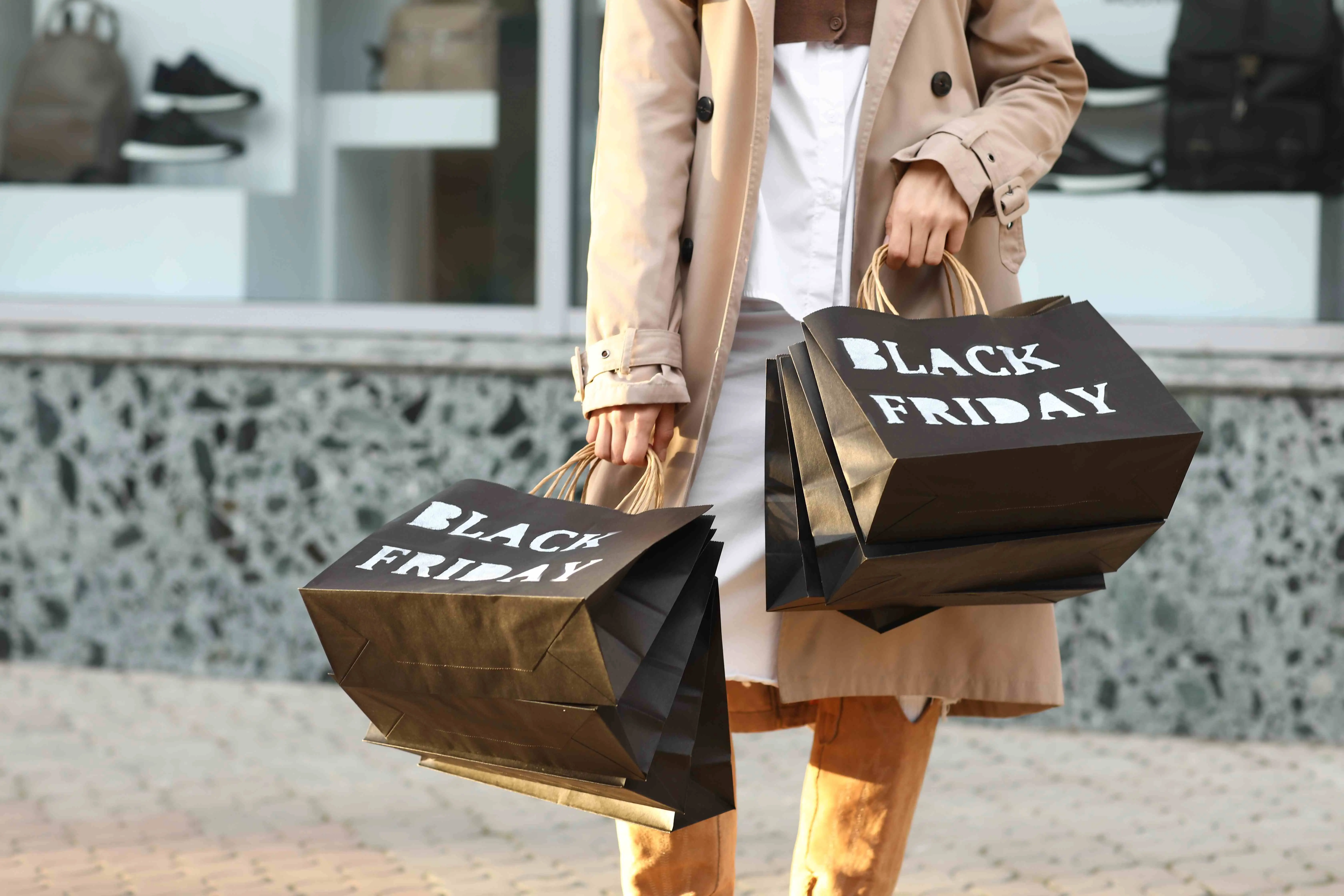 Uma pessoa segurando sacolas pretas com escritas brancas com o nome Black Friday.