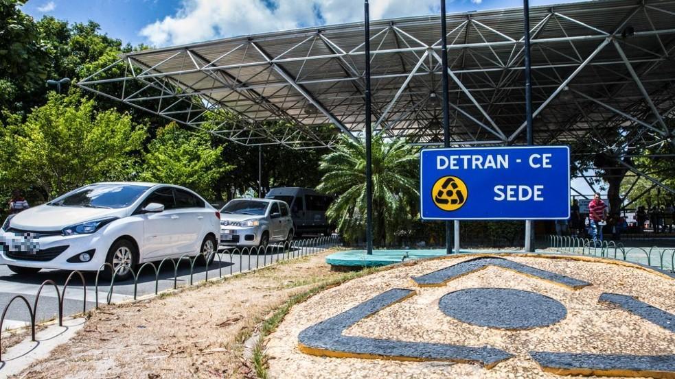 Uma imagem da porta de entrada do Detran com carros saindo
