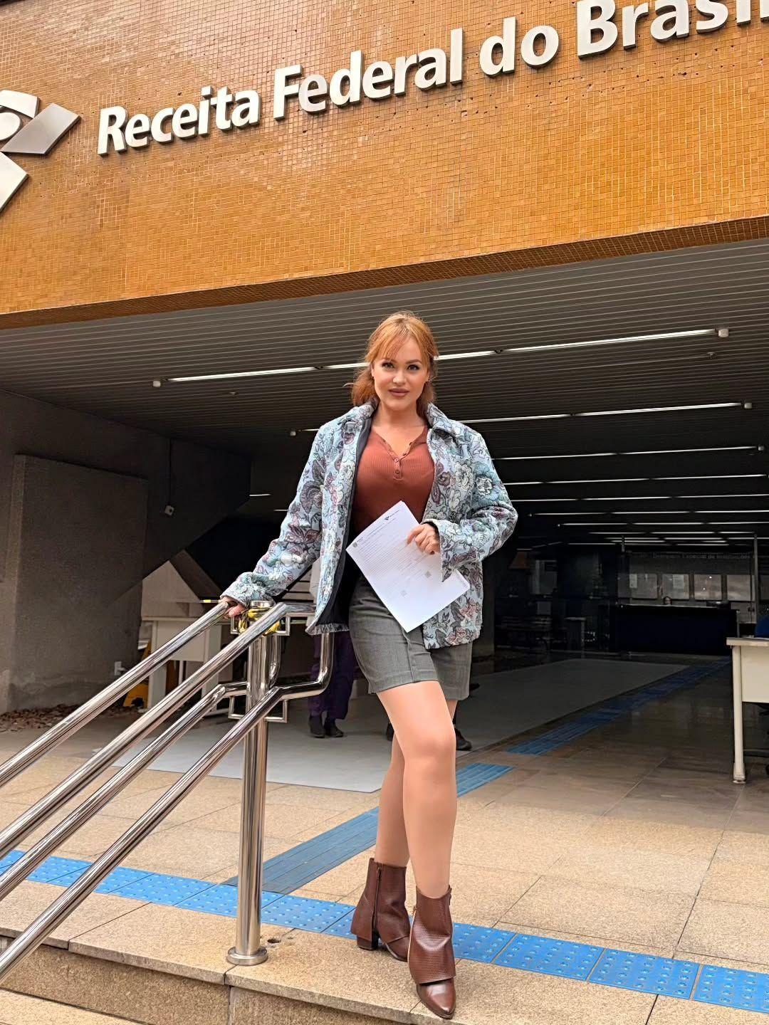 Gaby Spanic segurando documentos em frente à entrada da Receita Federal do Brasil.
