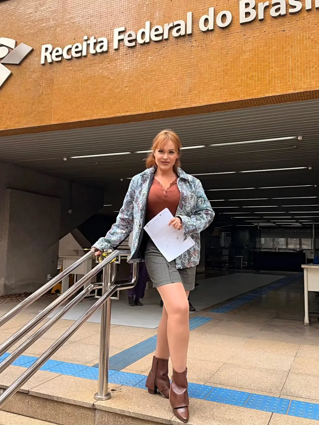 Gaby Spanic segurando documentos em frente à entrada da Receita Federal do Brasil.