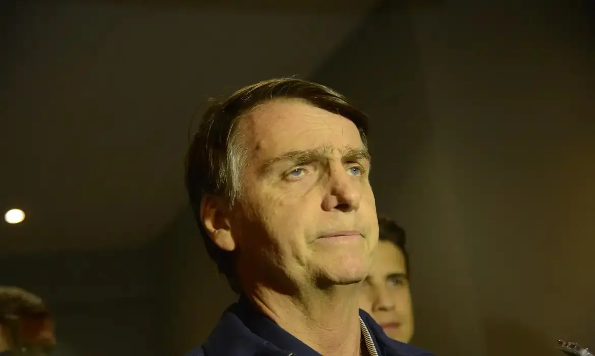 Jair Bolsonaro observa alguma coisa.