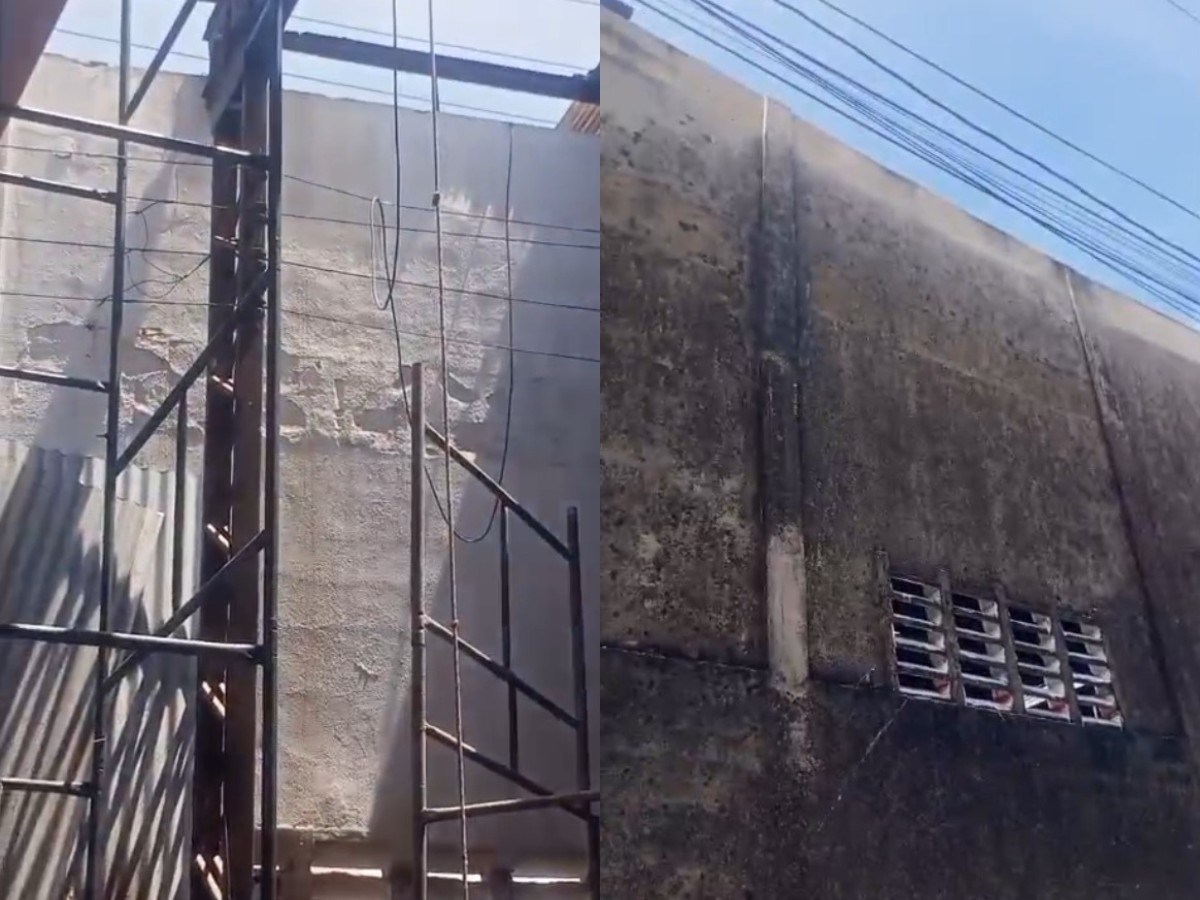 Duas paredes adjacentes com texturas e condições distintas: à esquerda, uma parede clara com andaimes e fios; à direita, uma parede escura e suja com fiação aérea e uma pequena janela.