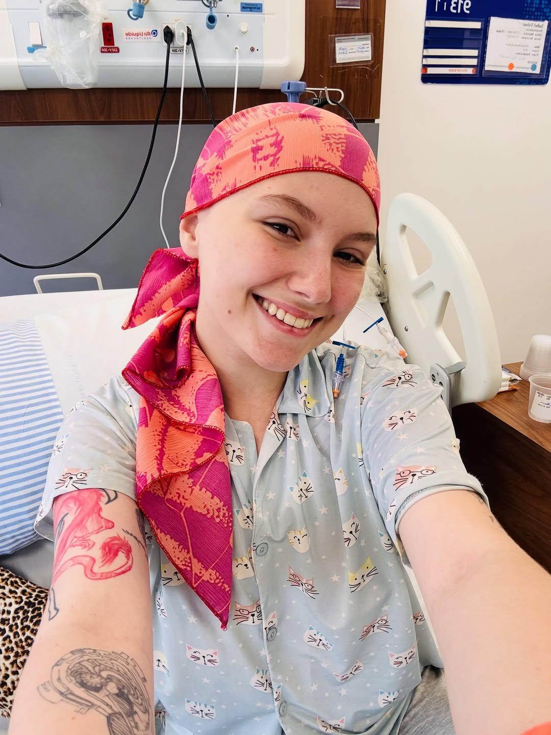 Isabel Veloso com lenço rosa na cabeça e em cama de hospital, onde se recuperou de transplante de medula óssea.