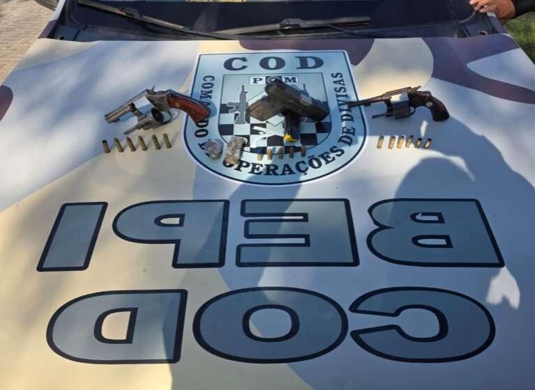 A imagem mostra três armas de fogo, munições e uma pequena quantidade de droga apreendidas com suspeitos, em cima de uma viatura da Polícia Militar do Ceará.
