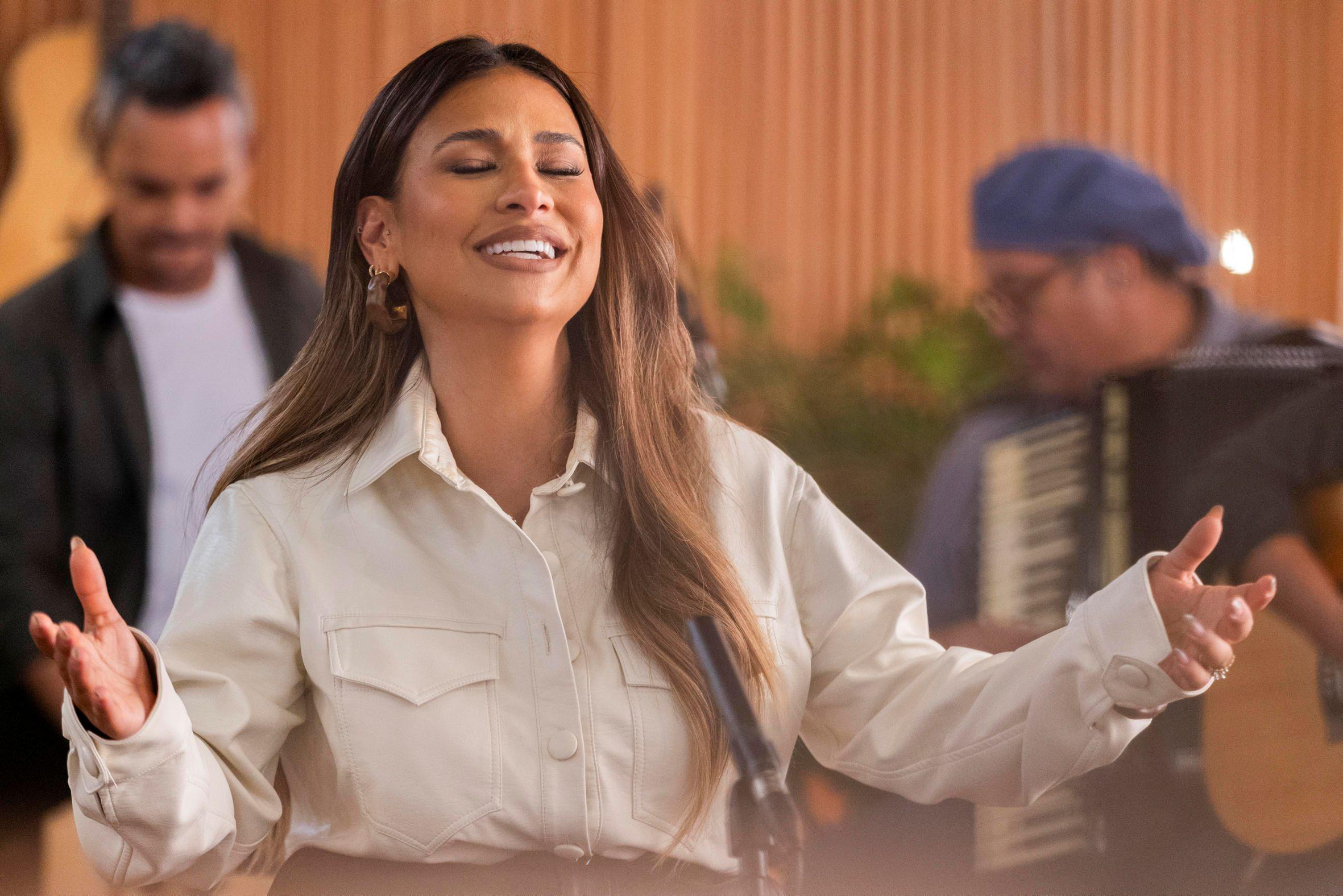 Simone Mendes cantando. ela está com olhos fechados e braços abertos.