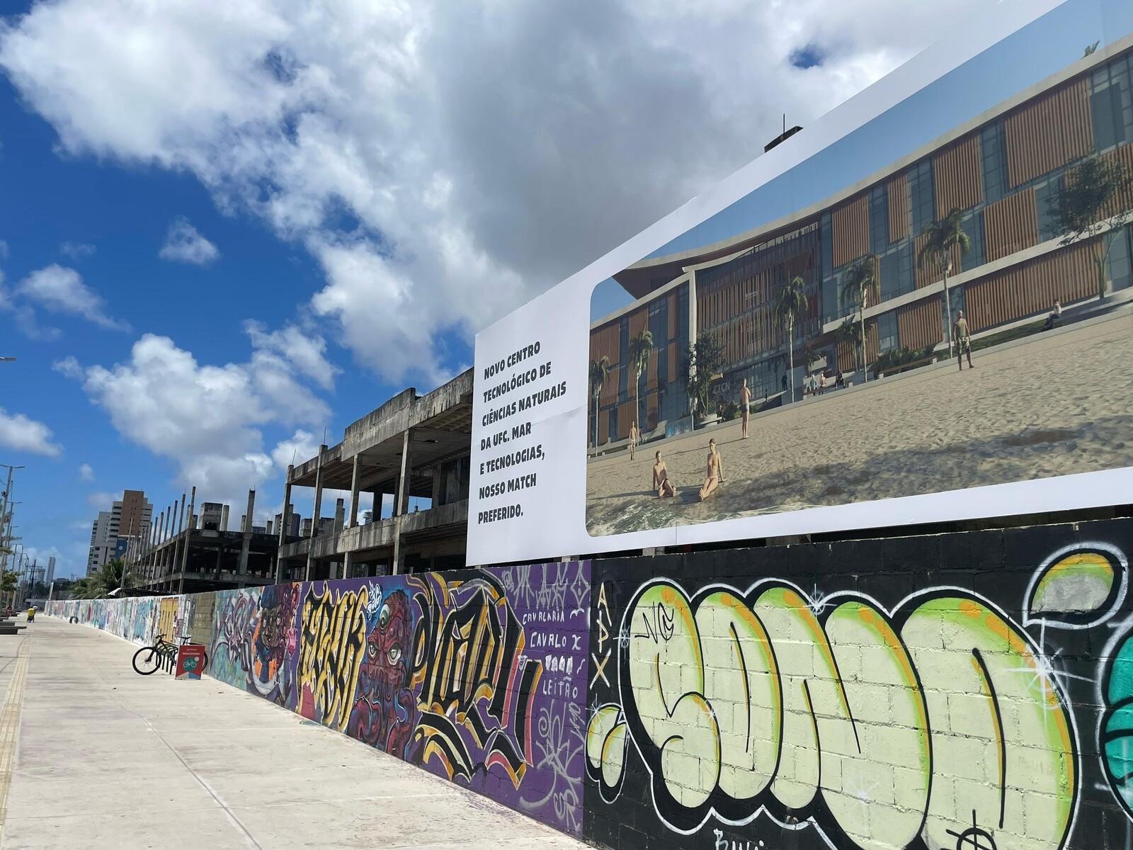 Imagem mostra fachada do antigo Acquario Ceará, com banner mostrando maquete eletrônica de como o espaço ficará após construção do Campus Iracema da UFC.