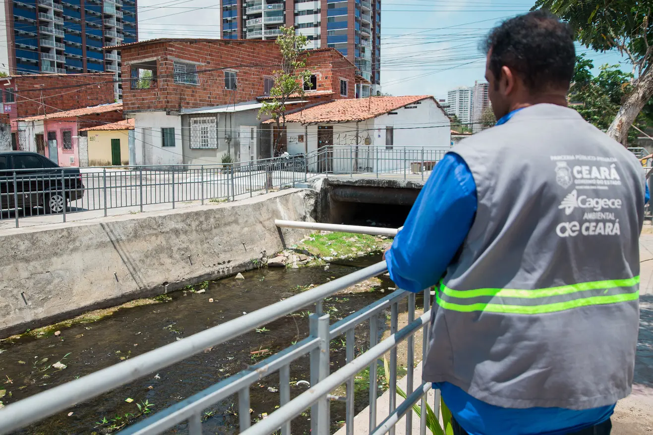 Agente da Ambiental Ceará diante de um canal em que corre esgoto durante um trabalho de conscientização sobre a importância do esgotamento.