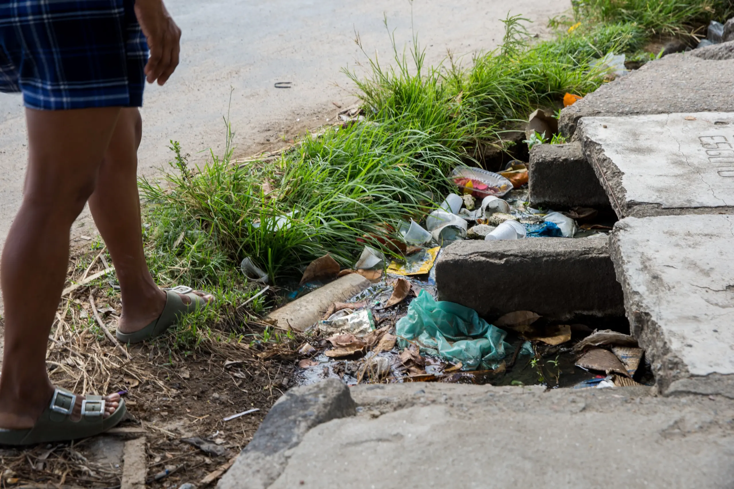 Imagem mostra pernas de uma mulher atravessando trecho de esgoto a céu aberto em Fortaleza.