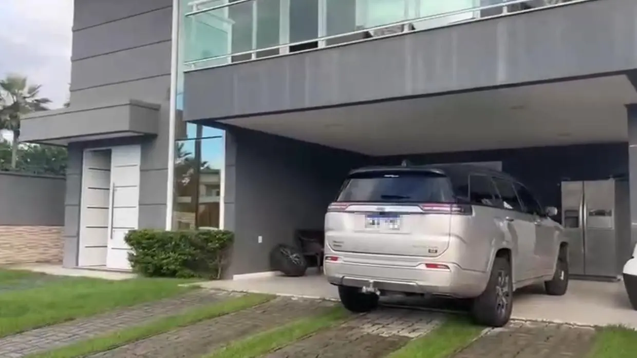 A imagem mostra um carro de luxo, de cor prata, estacionado na garagem de um imóvel em um condomínio no Eusébio.