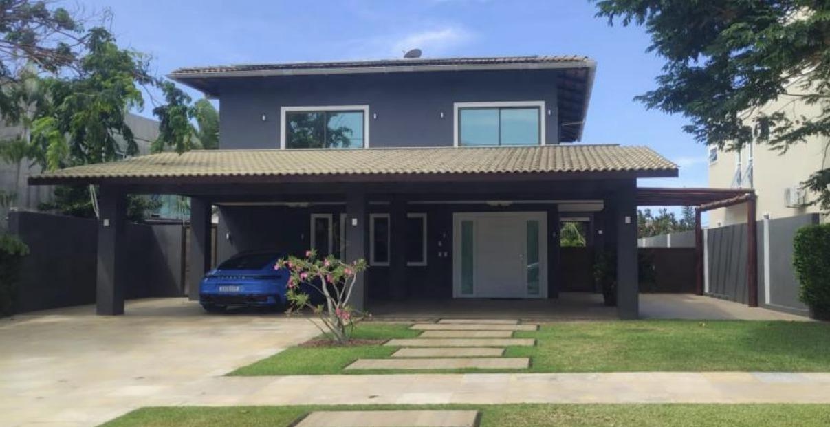 A imagem mostra um carro de luxo, de cor azul, em uma casa localizada num condomínio no Eusébio.