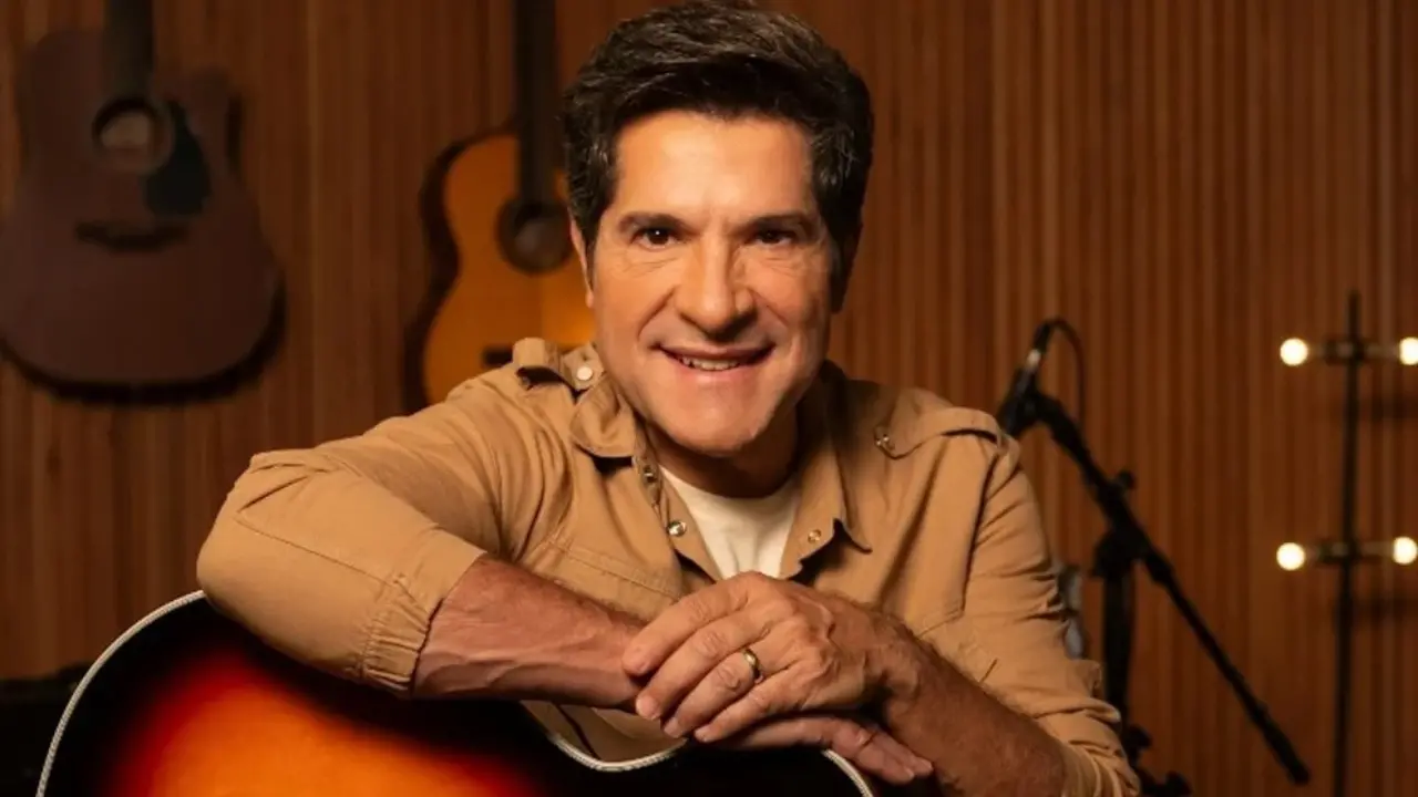 Cantor Daniel vestindo blusa caramelo e segurando um violão da cor bege.