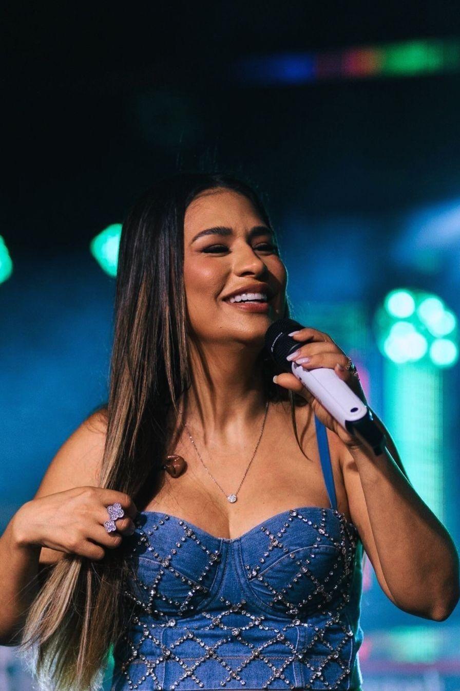 Imagem mostra Simone Mendes no palco, com um microfone branco na mão.