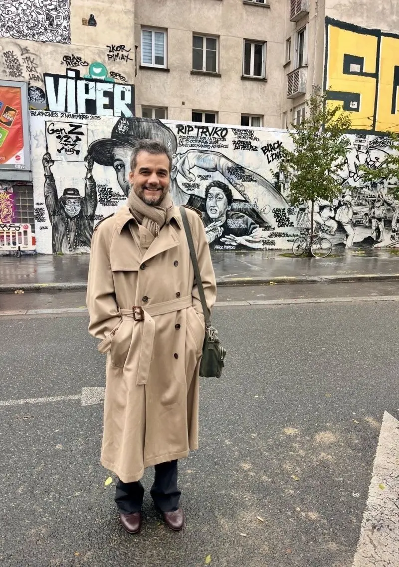 Wagner Moura usa casaco bege e sorri para a foto.