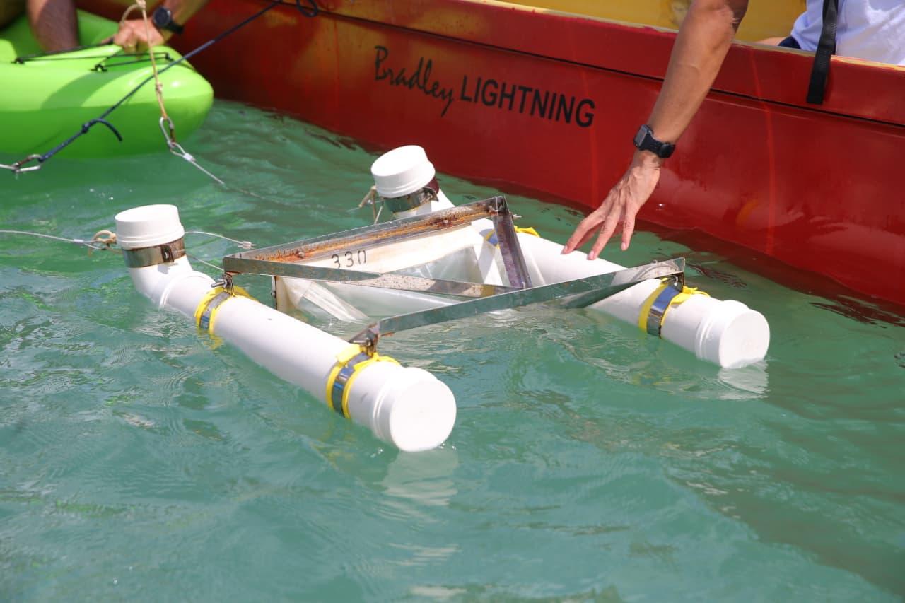 Veículo de pesquisa autônomo em teste na água, equipado com sensores e estrutura robusta, conectado a embarcações e analisando o ambiente aquático.