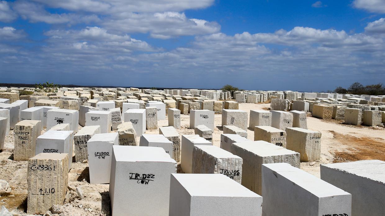 Blocos de rochas ornamentais enfileirados em área aberta.
