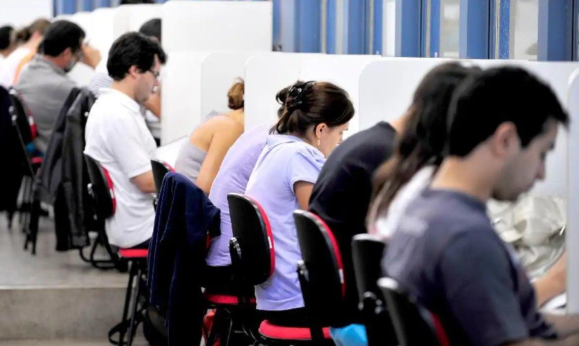 Estudantes ou candidatos concentrados em mesas individuais durante sessão de estudo preparatória para concurso público.