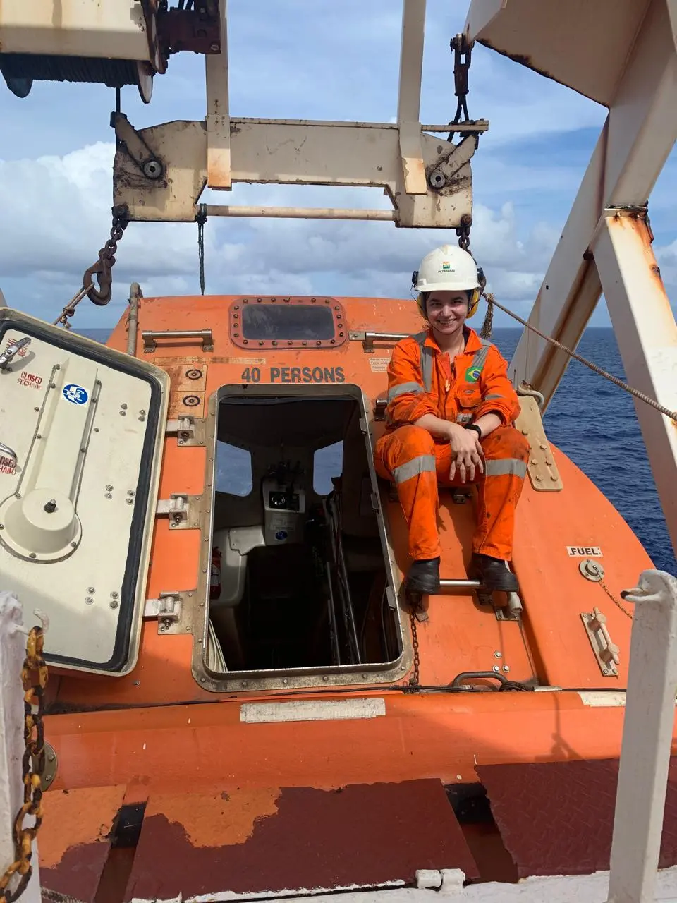 Mulher entada em parte de embarcação no mar.