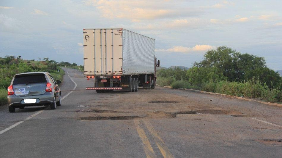 Foto que contém caminhão desviando de trecho esburacado em estrada do Ceará.