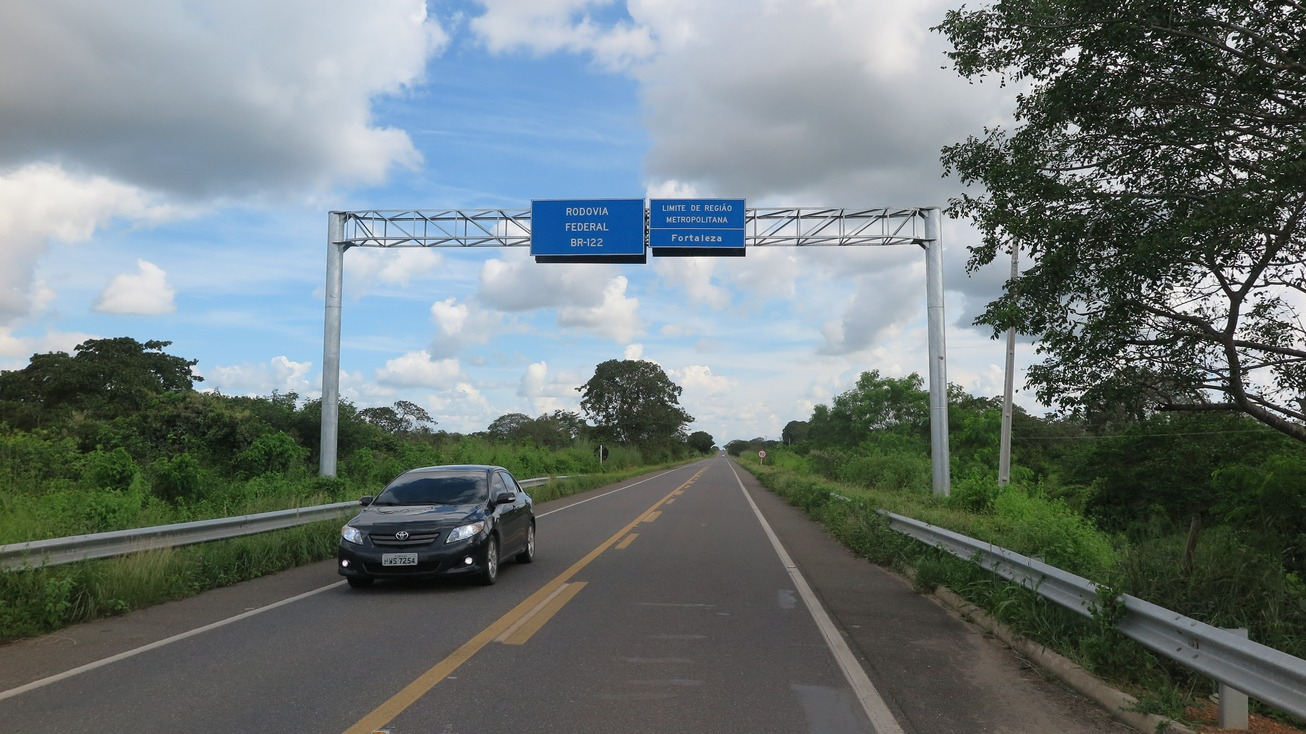 Foto que contém placa indicativa de trecho de Região Metropolitana na BR-122.