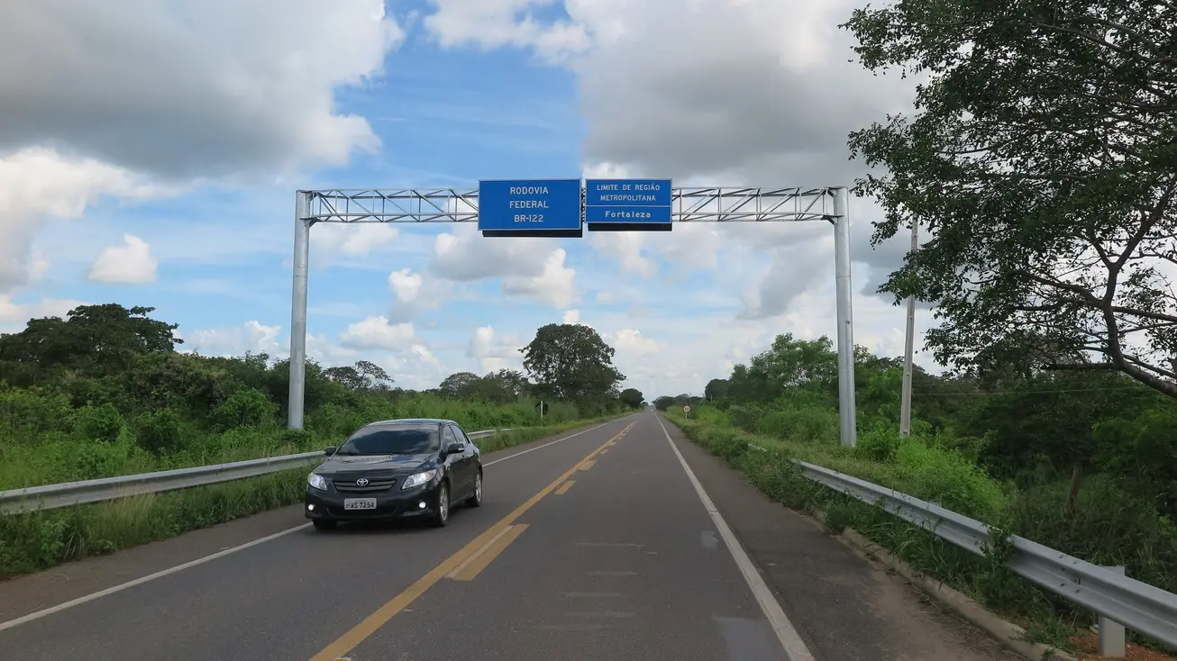 Foto que contém placa indicativa de trecho de Região Metropolitana na BR-122.