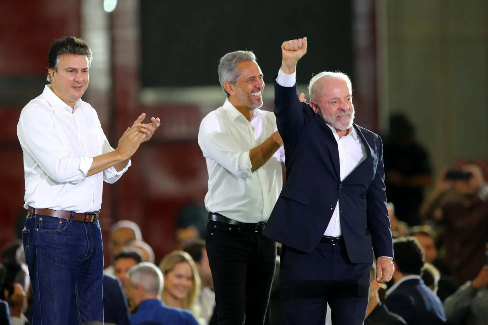 Lula faz gesto com a mão cerrada enquanto é aplaudido por Camilo e Elmano