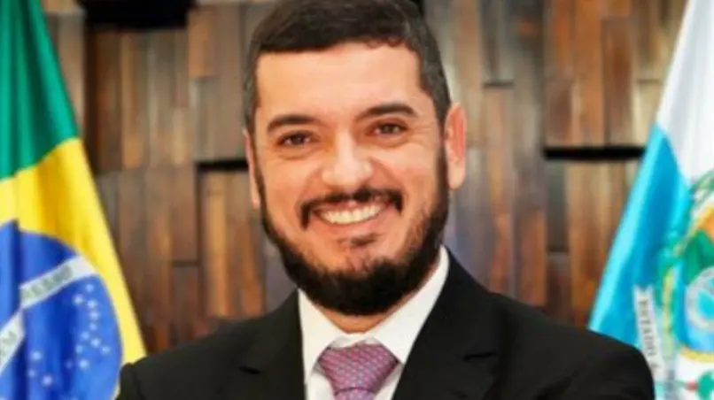 Foto oficial de Rodrigo Bacellar. Ele é um homem jovem de barba espessa e cabelo curto preto. Na foto, está de terno preto, camisa social branca e gravata roxa.