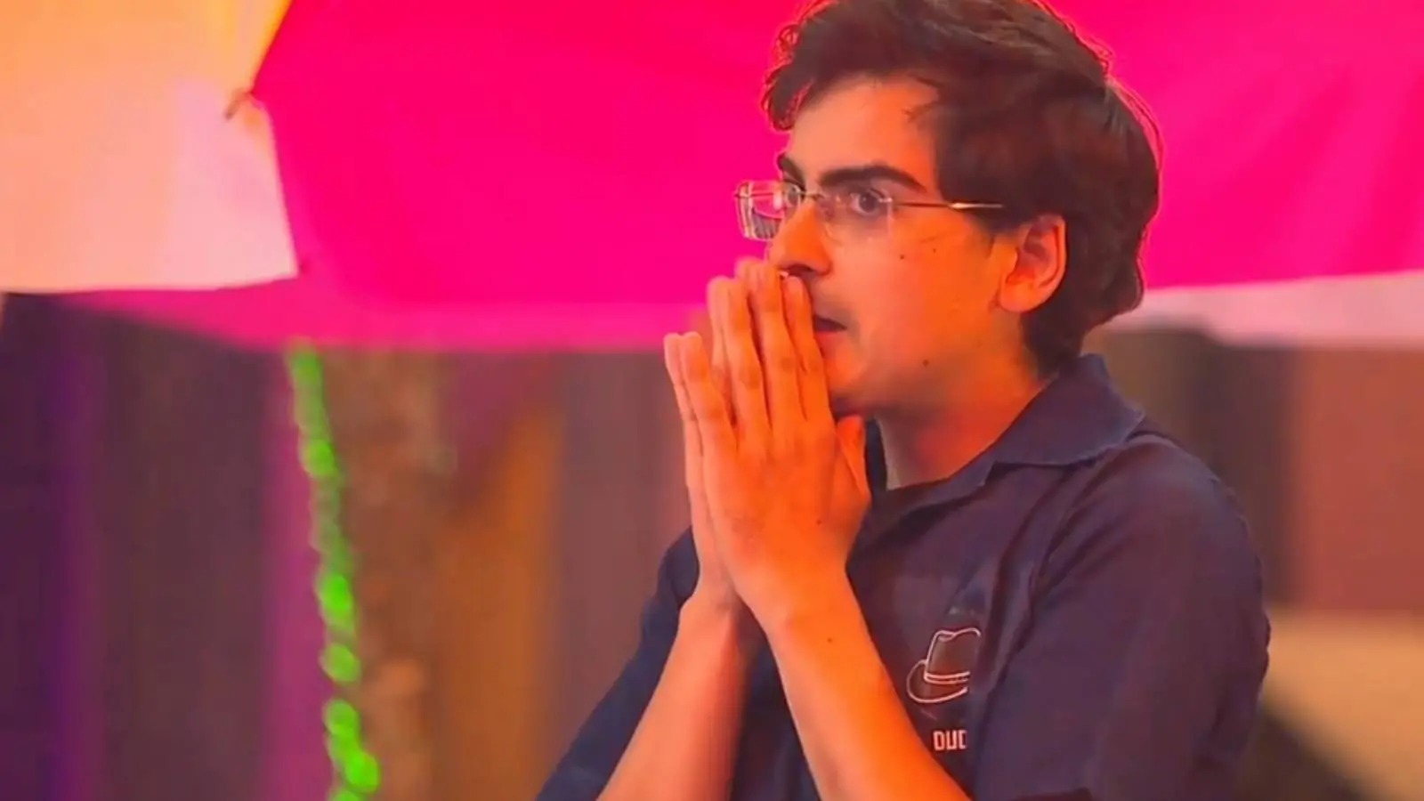 Imagem mostra Dudu Camargo, participante do reality show a Fazenda, durante a Prova do Fazendeiro, usando macacão azul com gola polo e logotipo de um chapéu, com expressão de concentração ou apreensão.