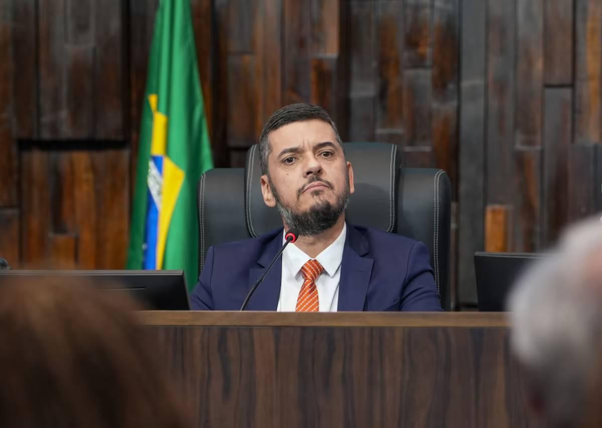 Imagem mostra Rodrigo Bacellar. Ele é um homem de meia idade e barba espessa. Na foto, ele está sorrindo e usa terno preto com camisa social branca e gravata lilás.