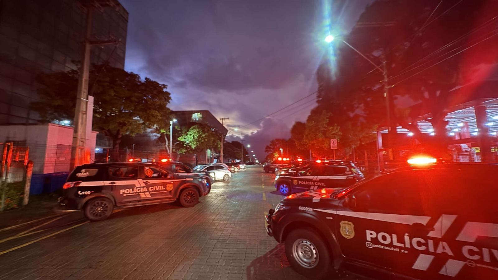 A imagem mostra viaturas da Polícia Civil e outros carros, em uma rua, próximo a prédios, durante uma operação policial no Ceará.