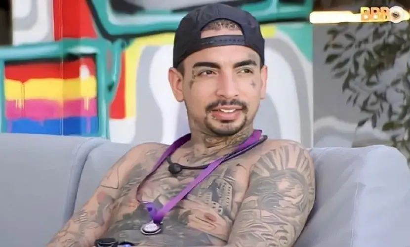 MC Guimê é um homem branco com o corpo todo tatuado e cavanhaque. Na foto, ele está sem camisa e usa boné para trás.