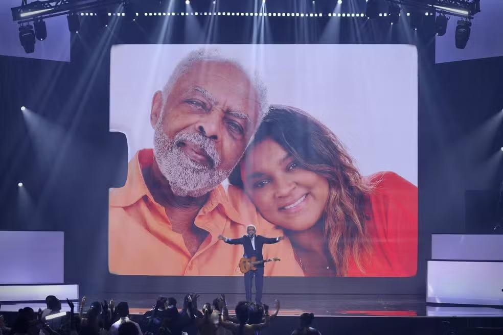 foto de Gilberto Gil se apresentando no prêmio Multishow 2025. Ao fundo, no telão, há uma foto do artista com a filha, Preta Gil.