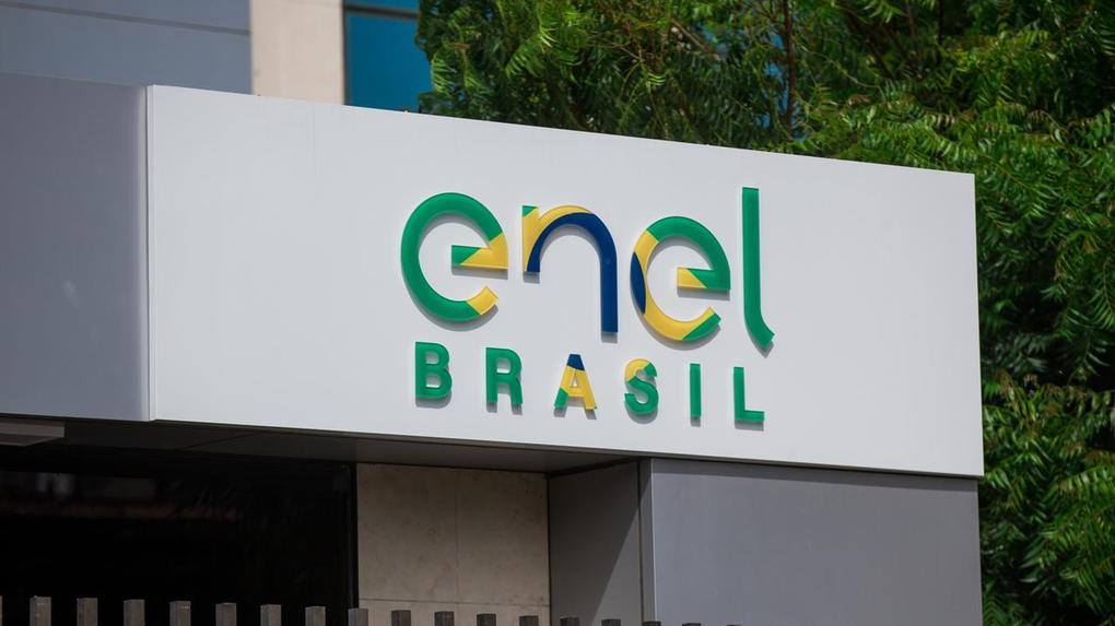 Logotipo da Enel Brasil em fachada corporativa, com letras estilizadas nas cores verde, azul e amarelo, representando a empresa de energia elétrica no Brasil.