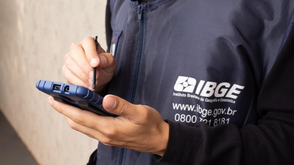 Funcionário do IBGE segura aparelho que coleta dados.