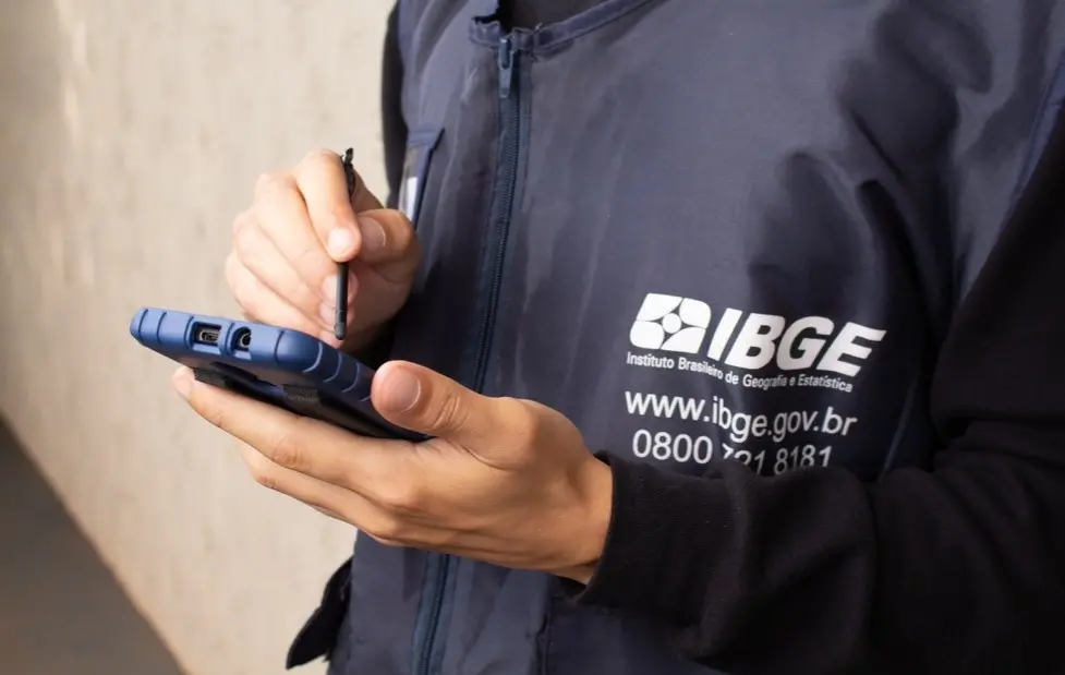 Funcionário do IBGE segura aparelho que coleta dados.