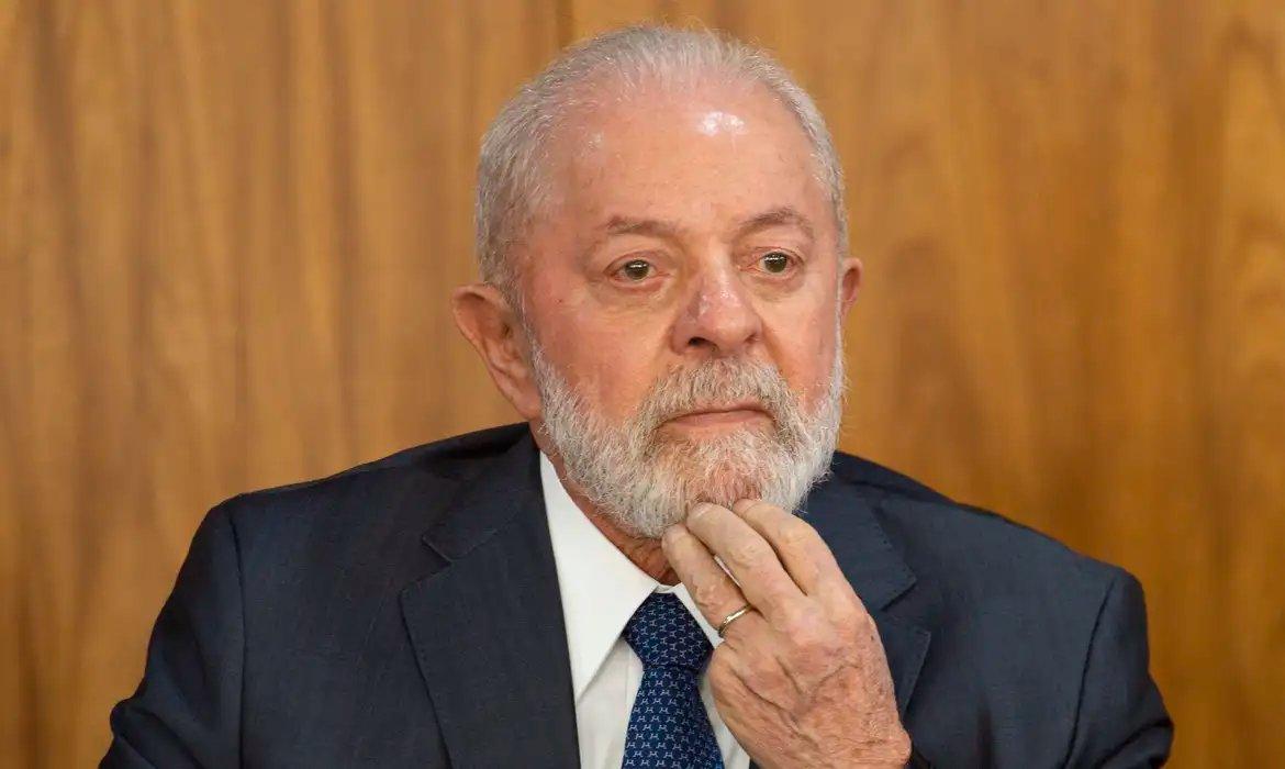 Luiz Inácio Lula da Silva, Presidente do Brasil, com expressão séria e reflexiva, tocando o queixo.