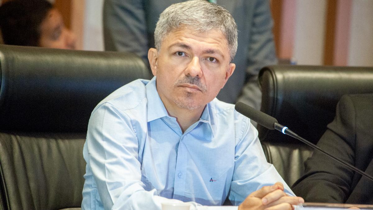 Wellington Macedo sentado, com uma camisa social azul, olha para a Câmera.