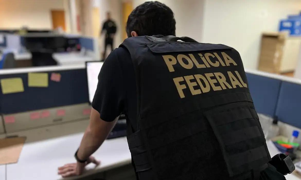 Agente da PF investiga em computador. Ele está de colete.