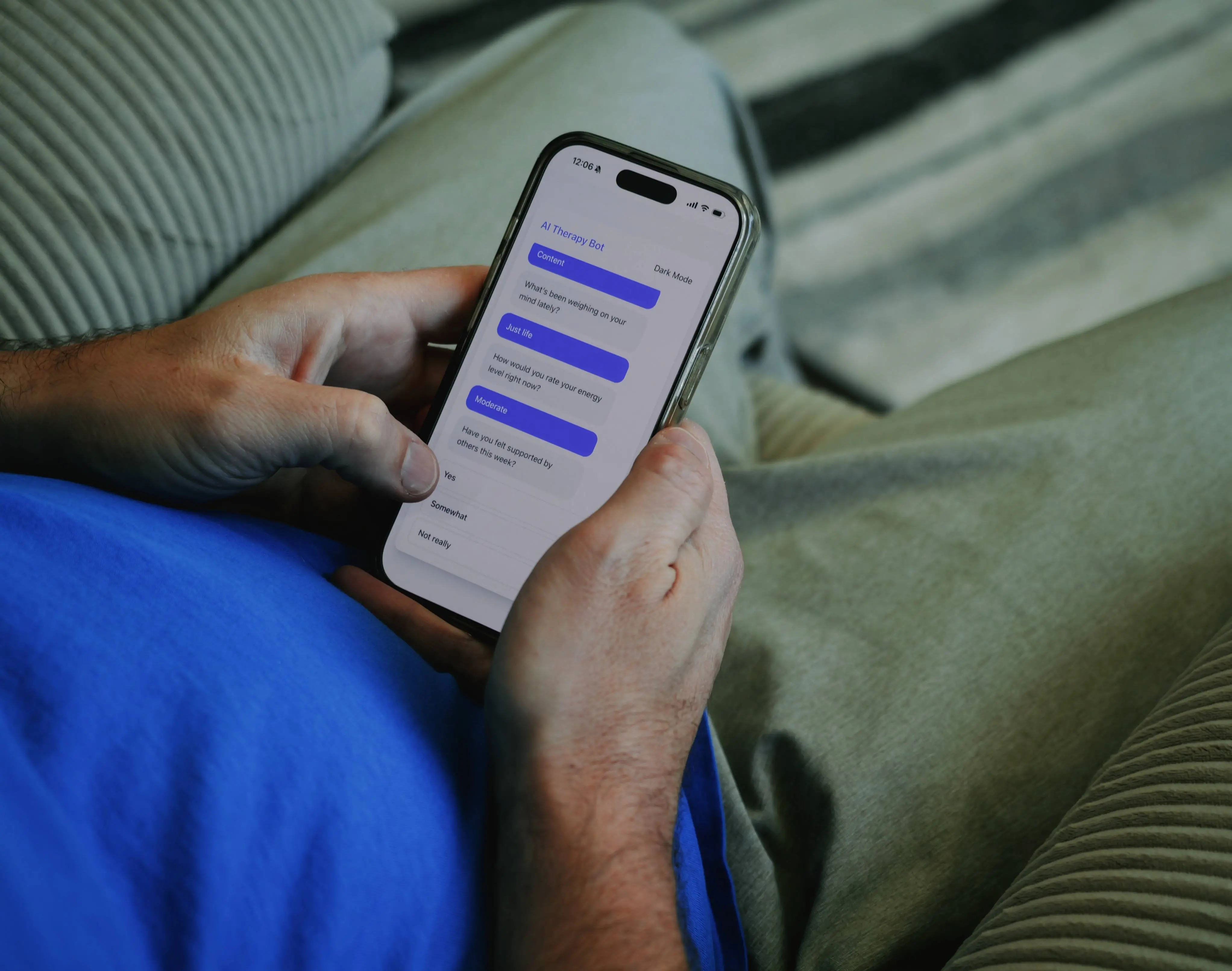 Pessoa segura um smartphone que exibe uma conversa com um chatbot de terapia por IA, enquanto está sentada em um sofá.