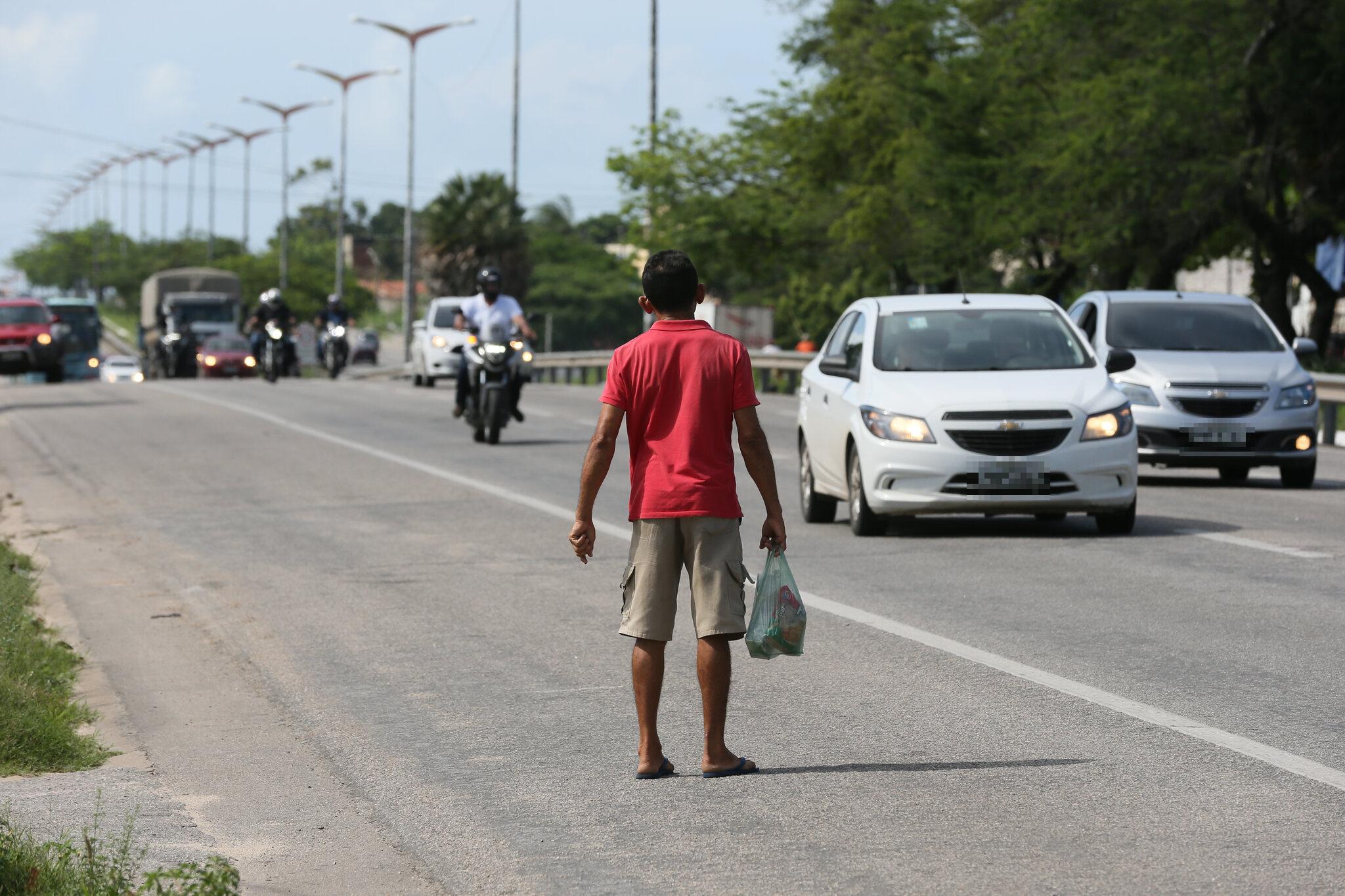 Homem observa trânsito da BR-116 antes de atravessar a via.